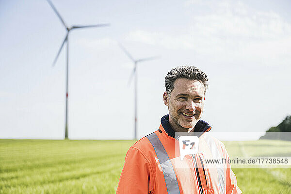 Lächelnder Ingenieur steht an einem sonnigen Tag im Feld