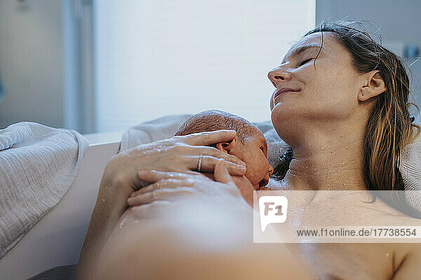 Mother relaxing with baby in bathtub