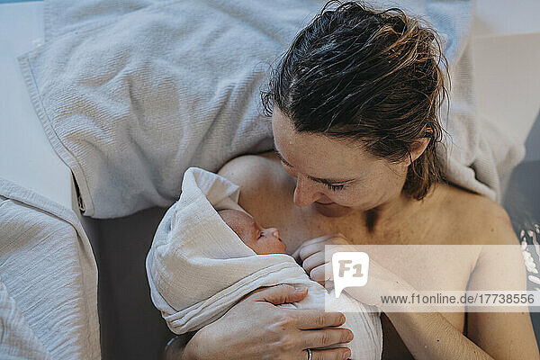 Mother holding baby wrapped in towel at home