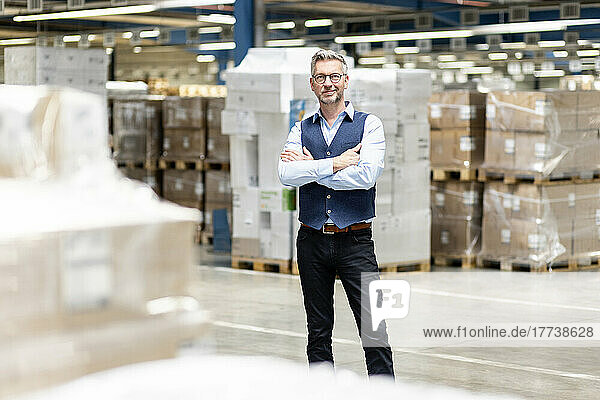Smiling manager standing with arms crossed in warehouse