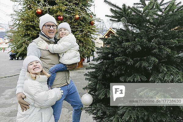 Happy father with daughters by Christmas tree