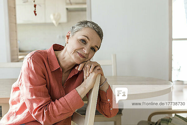 Porträt einer entspannten reifen Frau  die sich zu Hause auf einen Stuhl lehnt