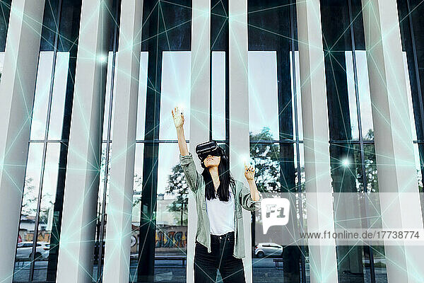 Woman wearing VR simulator with hand raised using transparent interface