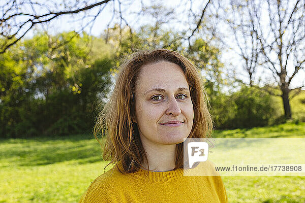 Lächelnde Frau mit braunen Haaren im Park