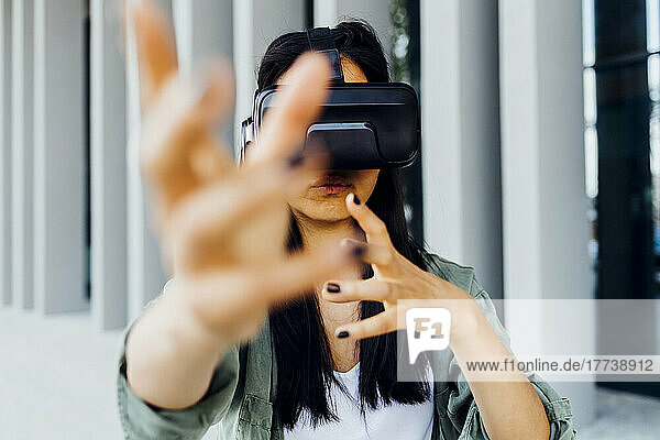 Frau mit Virtual-Reality-Simulator gestikuliert mit den Händen