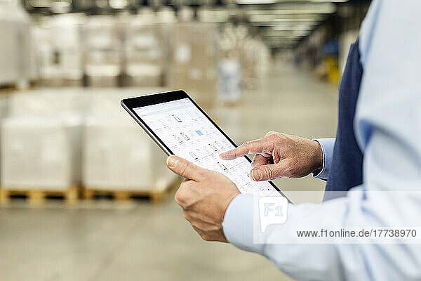 Hands of manager checking list through tablet PC in warehouse