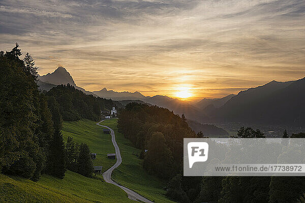 Germany  Bavaria  Wamberg  Sun setting over small road leading to remote village in Wetterstein mountains
