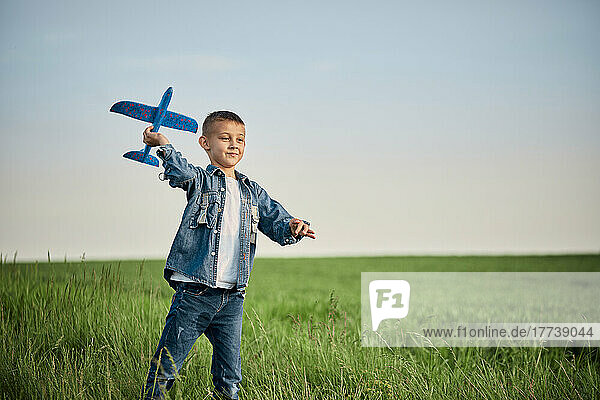 Boy playing with model on airplane in meadow
