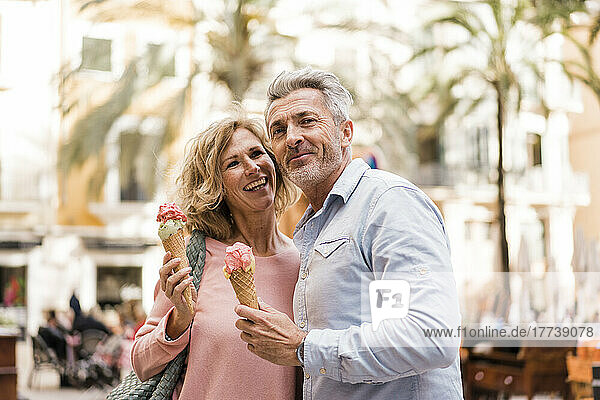 Cheerful woman having ice cream with man in city