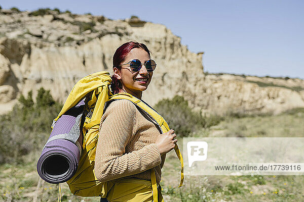 Smiling woman wearing sunglasses and backpack on sunny day