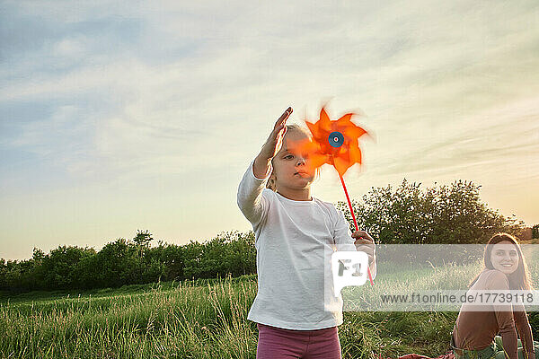 Girl playing with pinwheel toy in field on weekend