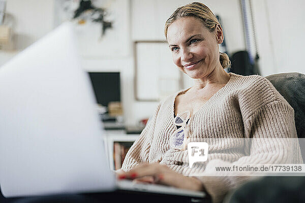 Happy woman using laptop at home
