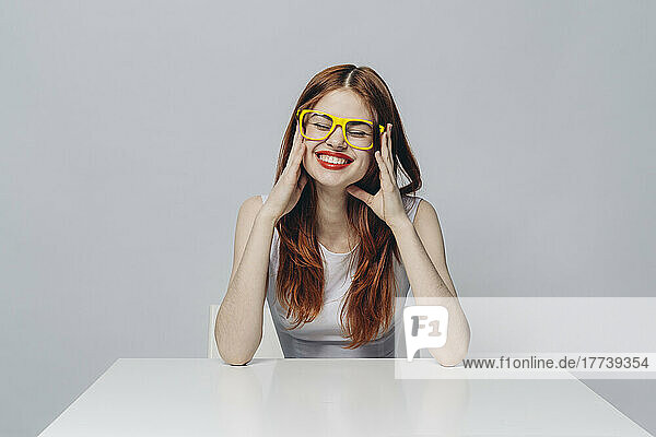Laughing Caucasian woman sitting at table wearing yellow eyeglasses