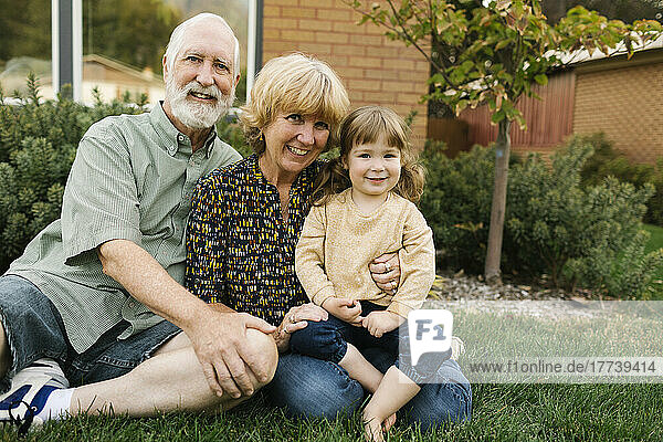 Portrait of smiling grandparents with granddaughter (4-5) on back yard