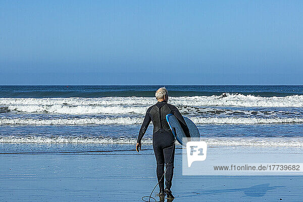 Senior surfer carrying surfboard
