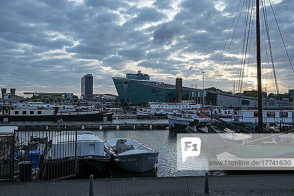Nemo Maritime Museum at sunrise  in front of excursion ships and houseboats  Amsterdam  Noord-Holland  Netherlands