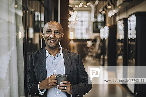 Portrait of bald businessman with coffee mug in creative office