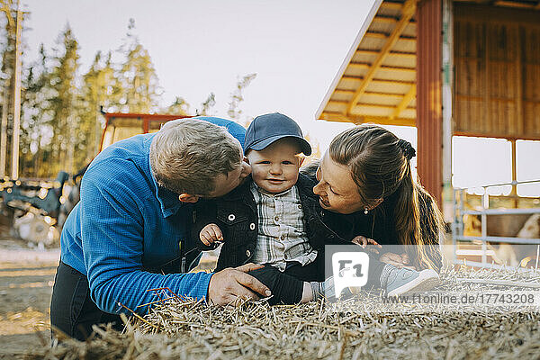 Parents looking at son sitting on hay bale