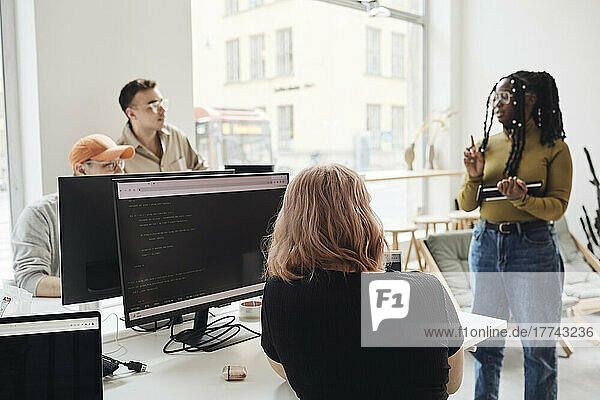 Female programmer giving presentation to colleagues during meeting in office