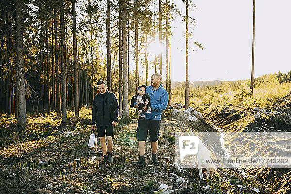 Parents with son and pet dog walking in forest