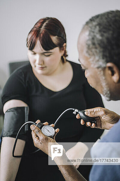Male healthcare expert examining blood pressure of female patient in medical clinic