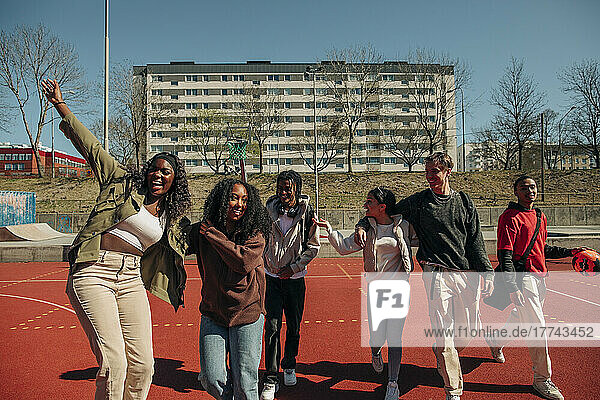 Fröhliche multirassische Freunde  die sich an einem sonnigen Tag auf einem Sportplatz vergnügen