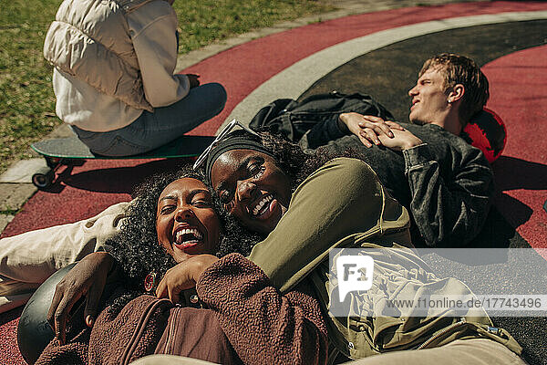 Happy young female friends lying on playground