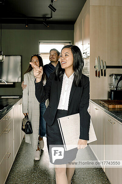 Immobilienmakler  der Kunden die Küche eines neuen Hauses zeigt