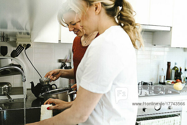 Frau macht Hausarbeit durch Freundin bereitet Tee in der Küche zu Hause