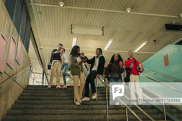 Männliche und weibliche Freunde  die sich auf den Stufen einer U-Bahn-Station vergnügen
