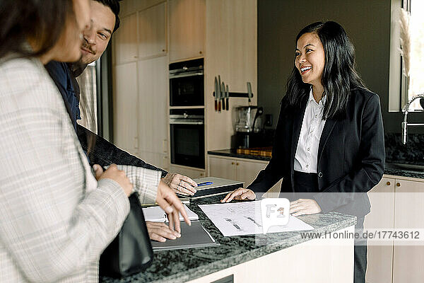 Lächelnder Immobilienmakler  der den Kunden die Unterlagen des neuen Hauses erklärt