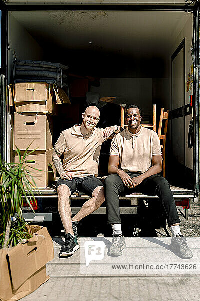 Portrait of smiling delivery men sitting in truck during sunny day