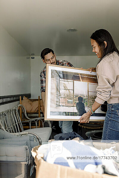 Ehepaar entlädt beim Umzug in ein neues Haus Gemälde vom Lastwagen
