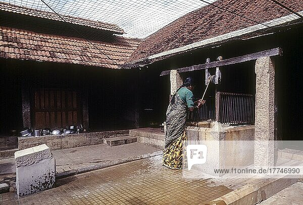 Eine Frau holt Wasser aus dem Brunnen  Haus von Nattukottai Chettiar in Kanadukathan in Chettinad  Tamil Nadu  Indien  Asien
