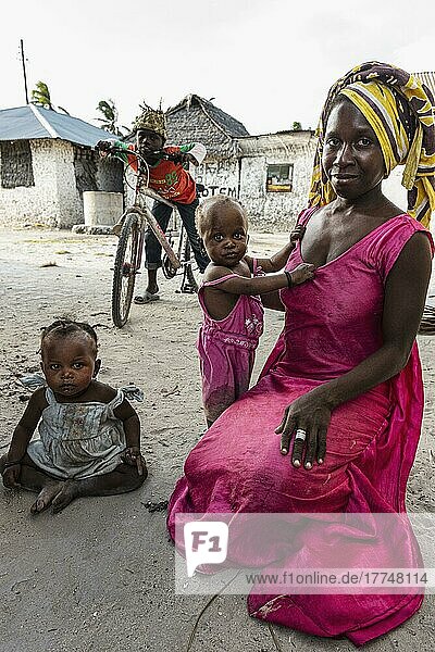 Mutter mit zwei Kindern  hinten Junge auf Fahrrad  rosa Kleid  Alltagsleben  Jambiani  Ostküste  Unguja  Sansibar  Tansania  Afrika