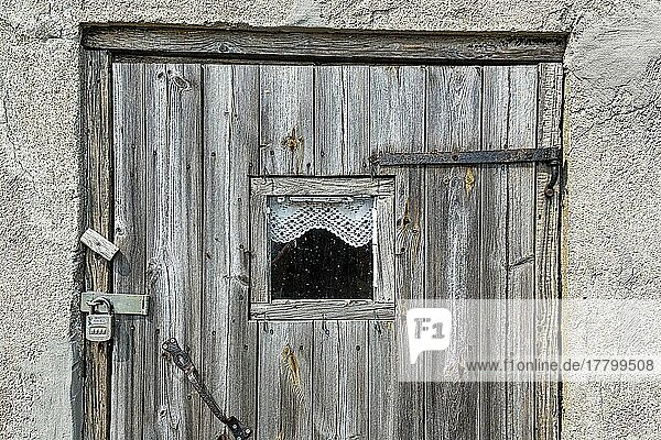 Alte braune Holztür mit Vorhängeschloss  Fenster und kleiner Gardine  Detailaufnahme  Fischerstelle  saisonal bewohntes Dorf an der Küste  Norebod Fiskeläge  Südgotland  Insel Gotland  Schweden  Europa
