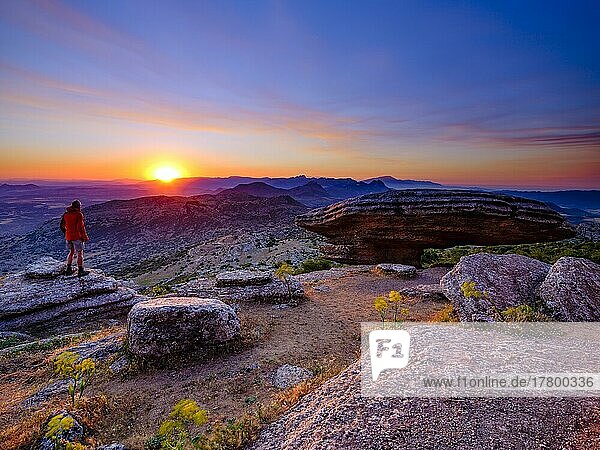 Hiker standing by the limestone Sombrerillo rock formation at sunrise  El Torcal nature reserve  Torcal de Antequera  Malaga province  Andalucia  Spain  Europe