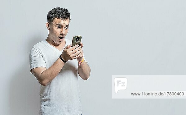 Handsome man with surprised expression with his phone in his hand  An astonished person with his cell phone on isolated background