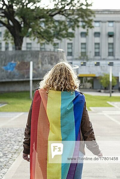 Back view of a lesbian activist on under LGBT rainbow flag. Concept of Pride. Pride month