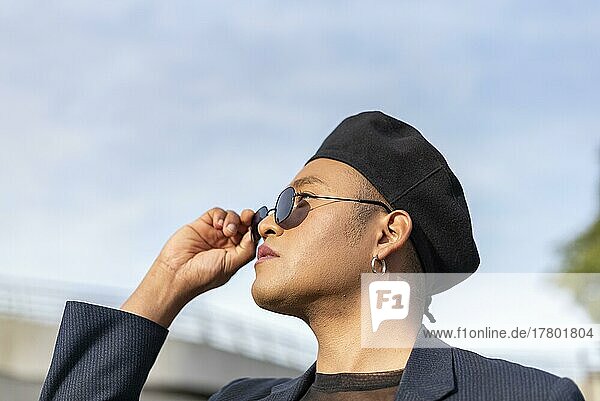 Young latin gay man with make-up on wearing a fashionable hat and looking over sunglasses up. LGBT. copy space