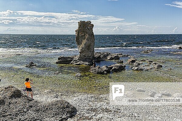 Hiker in front of rock needle on the coast  Raukar  limestone pillar in Digerhuvud Nature Reserve  Fårö Island  Farö  Gotland  Baltic Sea  Sweden  Europe