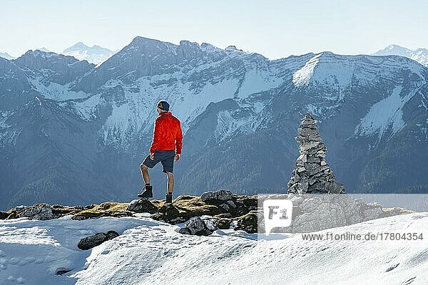 Mountaineer next to a cairn  in front of snowy mountains of the Rofan  hiking trail to the Guffert with first snow  in autumn  Brandenberg Alps  Tyrol  Austria  Europe