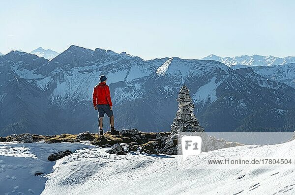 Bergsteiger neben einem Steinmännchen  vor verschneiten Bergen des Rofan  Wanderweg zum Guffert mit erstem Schnee  im Herbst  Brandenberger Alpen  Tirol  Österreich  Europa