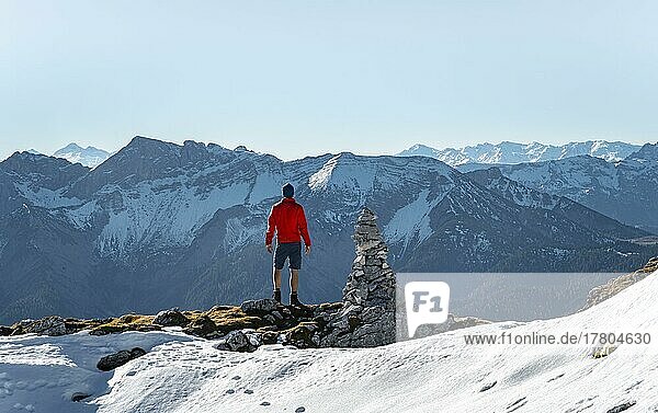 Mountaineer next to a cairn  in front of snowy mountains of the Rofan  hiking trail to the Guffert with first snow  in autumn  Brandenberg Alps  Tyrol  Austria  Europe