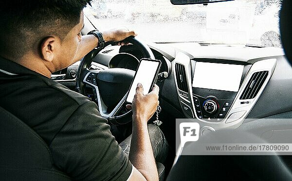Person holding the cell phone and with the other hand the steering wheel  Distracted driver using the cell phone while driving  Man using his phone while driving  Concept of irresponsible driving