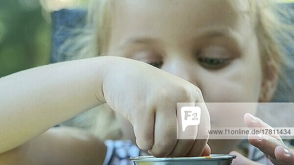 Kleines Mädchen essen Pommes frites. Close-up von blonden Mädchen nimmt Kartoffelchips mit ihren Händen und probiert sie sitzen in Straßencafé auf dem Park. Odessa  Ukraine  Europa