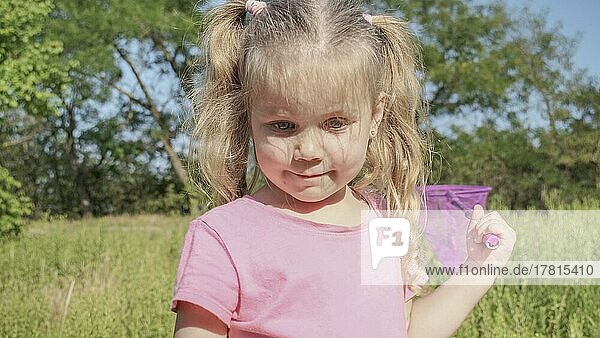 Kleines Mädchen spielt mit Schmetterlingsnetz von hohem Gras im Stadtpark. Nettes kleines Mädchen spielt mit Luftinsektennetz in Wiese auf Sonne Tag. Odessa  Ukraine  Europa