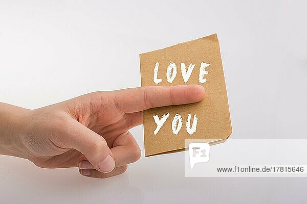 Love You Text auf Papier in der Hand über weißem Hintergrund