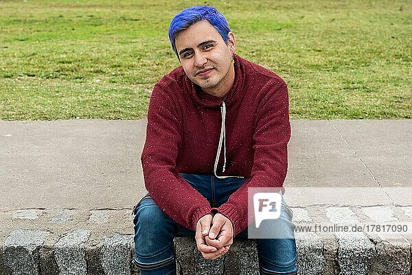 Portrait of a young man with blue hair looking at camera outdoors