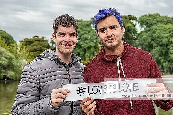 Ein homosexuelles Paar zeigt ein Liebe ist Liebe Zeichen. LGBT Konzept